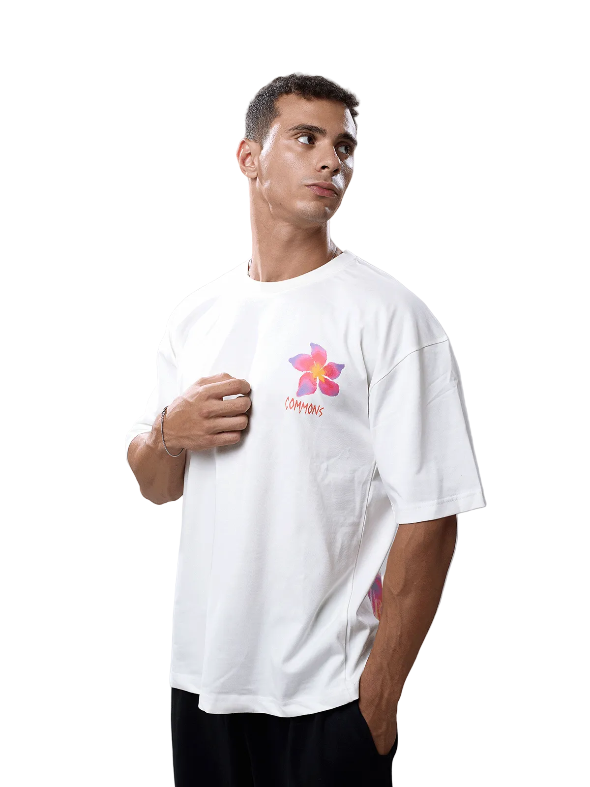 A man wearing a white oversized t-shirt with a colorful flower graphic and the word 'CAMPING' printed on the chest, posed against a solid gray studio background.