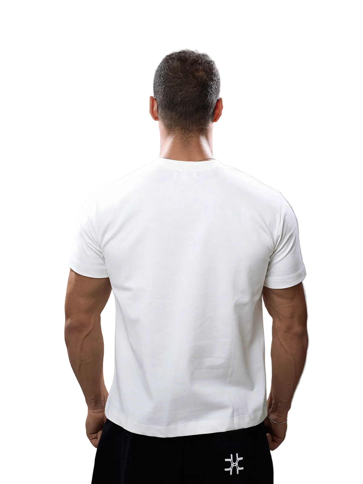 A man viewed from behind wearing a plain white short-sleeve crew-neck t-shirt and black pants against a solid gray studio background.