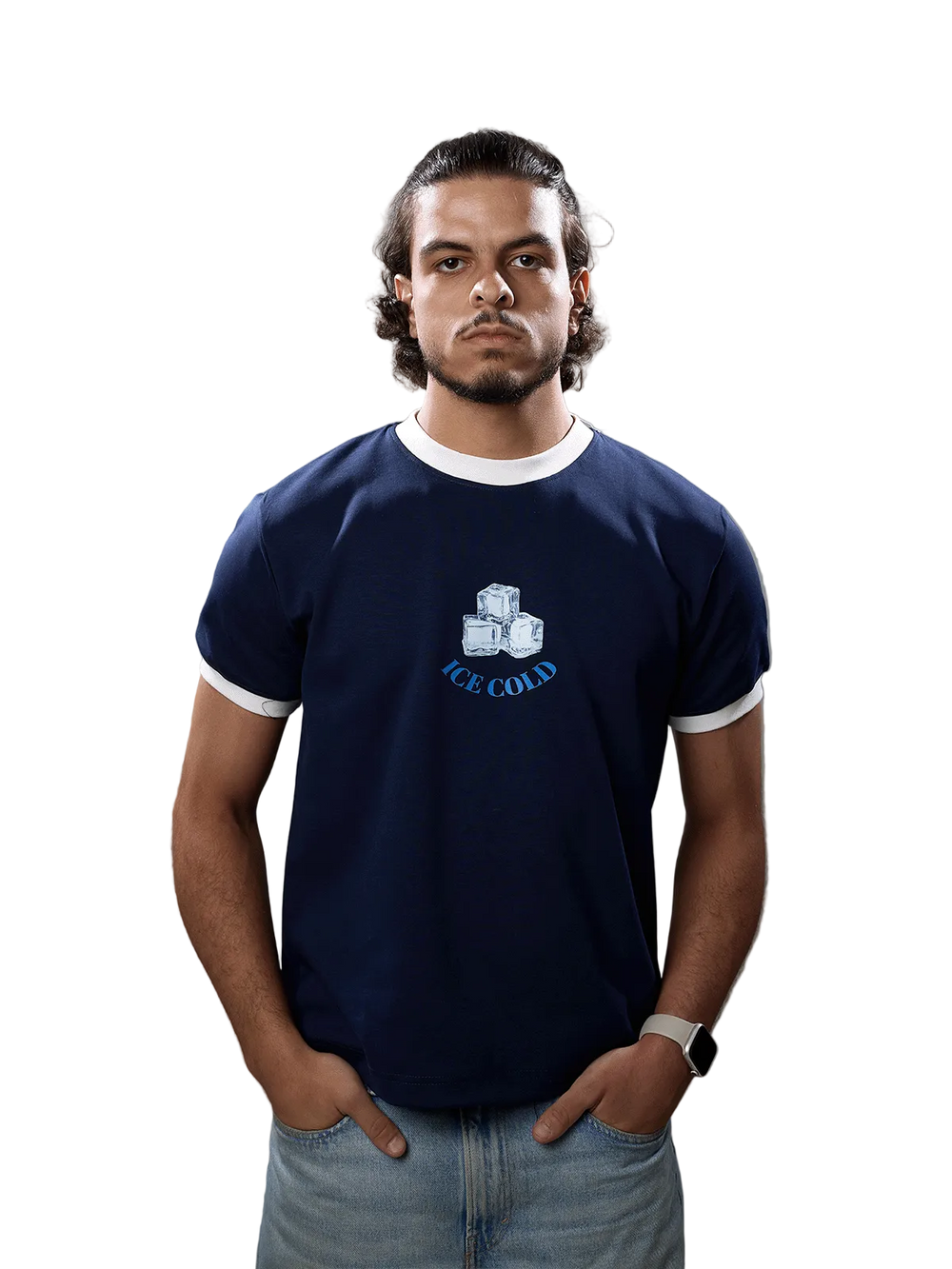 A man wearing a navy blue ringer t-shirt with white trim and a graphic of ice cubes and the text 'ICE COLD' on the chest, paired with light blue jeans, standing against a solid gray background.