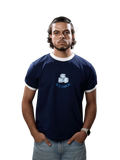 A man wearing a navy blue ringer t-shirt with white trim and a graphic of ice cubes and the text 'ICE COLD' on the chest, paired with light blue jeans, standing against a solid gray background.