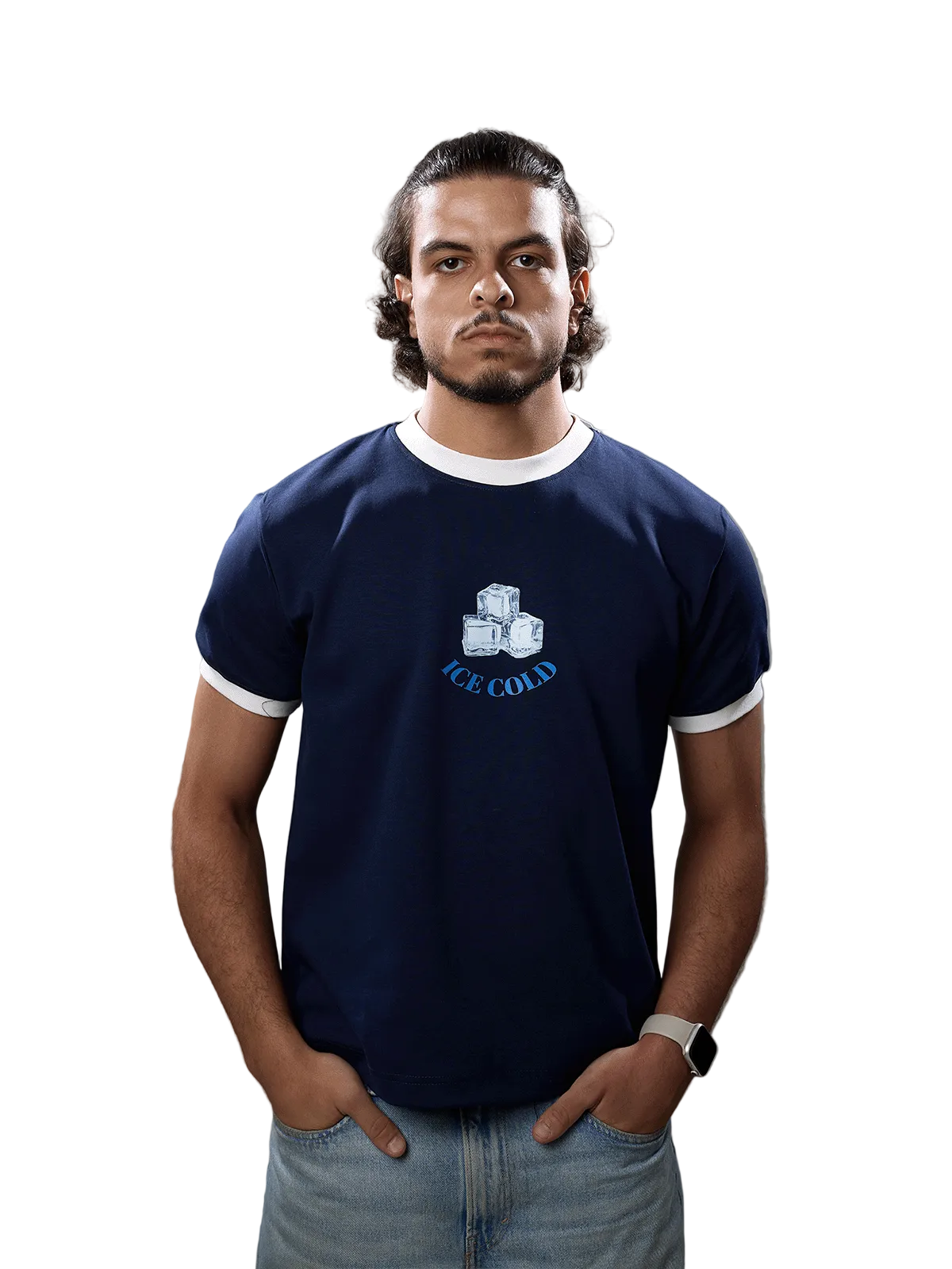 A man wearing a navy blue ringer t-shirt with white trim and a graphic of ice cubes and the text 'ICE COLD' on the chest, paired with light blue jeans, standing against a solid gray background.
