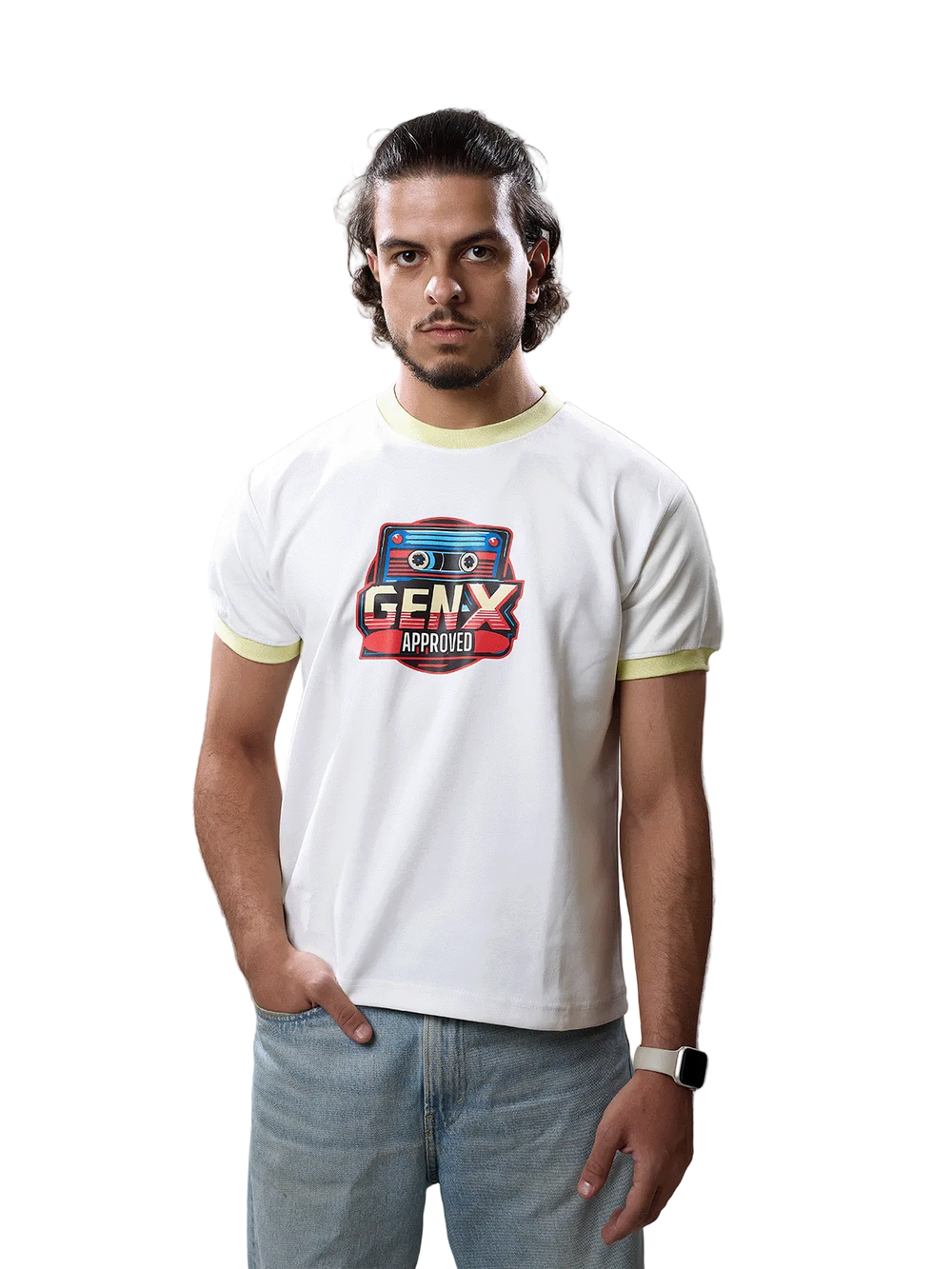 A man wearing a white ringer t-shirt with a retro cassette graphic that reads 'GENX APPROPRIATE' in red, blue, and yellow, paired with light blue jeans, standing against a solid gray studio background.